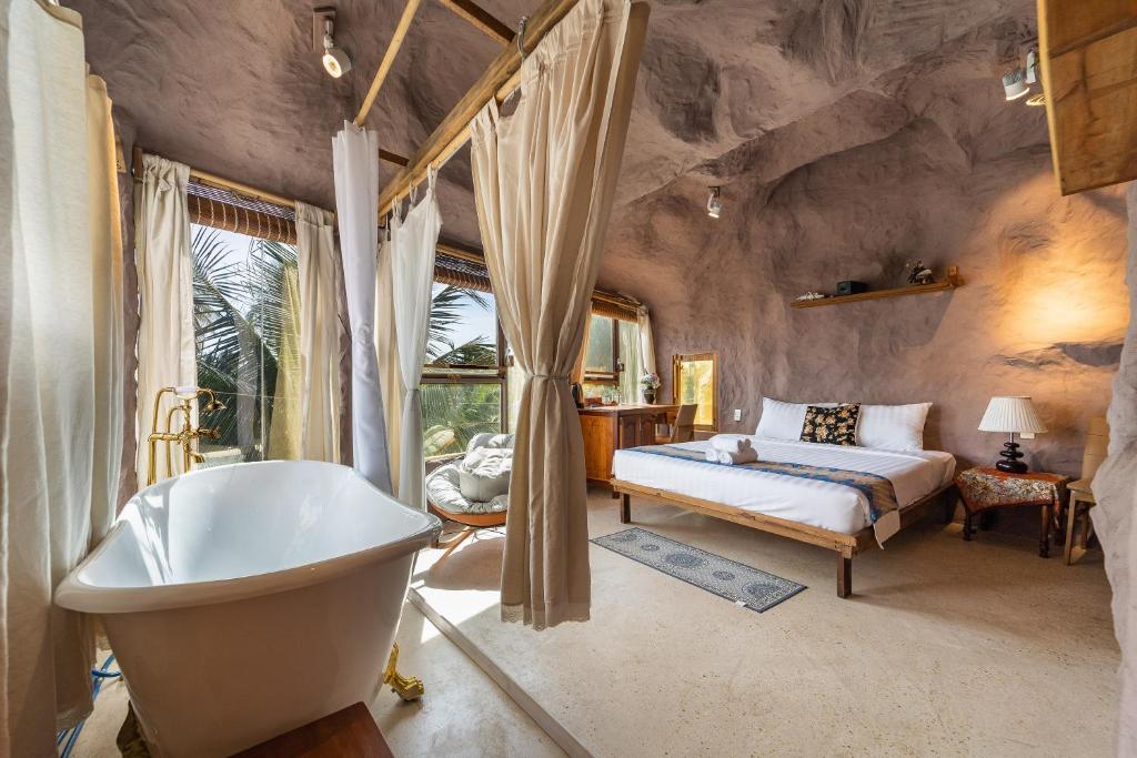 a bathroom with a bed and a bath tub and a sink at OXY Cave Homestay Mũi Né in Mui Ne