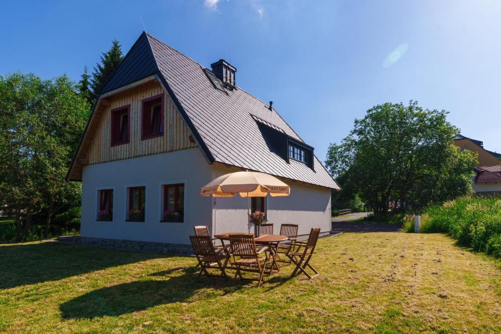 a table with chairs and an umbrella in front of a house at Domecheck Boží Dar in Boží Dar