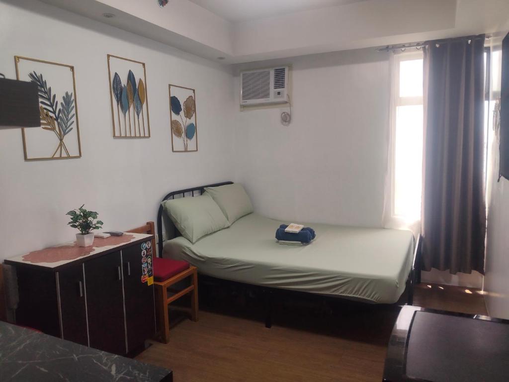 a small room with a bed and a window at Staycationbabe in Manila