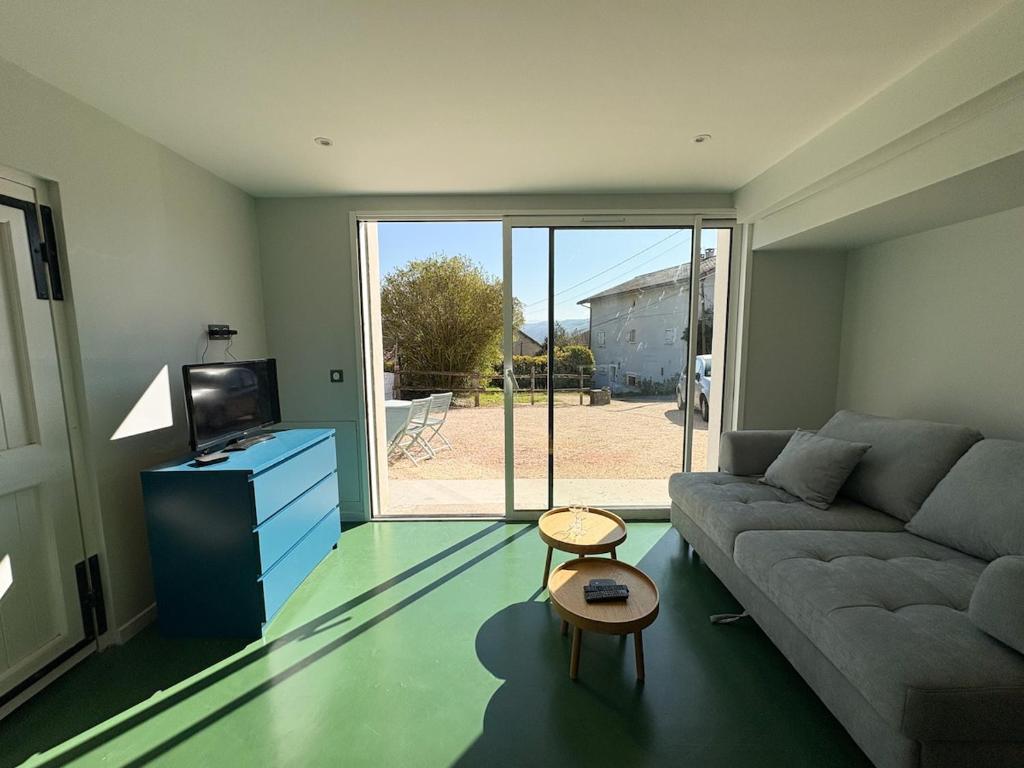 a living room with a couch and a tv at L'échappée verte in Chirens