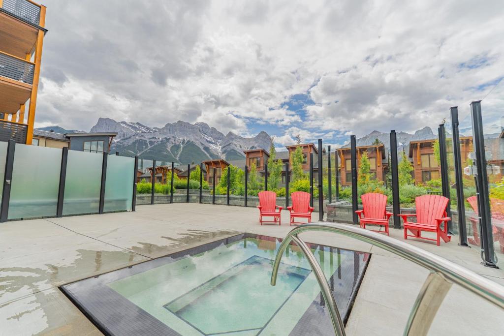 a patio with chairs and a hot tub with mountains at Spring Creek Corner Condo by Canadian Rockies Vacation Rentals in Canmore