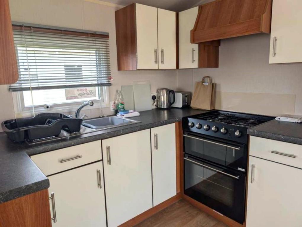 a kitchen with a sink and a stove top oven at Seashell Cove - 2 bedrooms sleeps 6 in Dymchurch