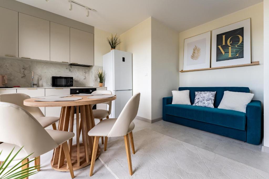 a kitchen and living room with a blue couch and a table at Rumia Stylish Apartment by BookingHost in Rumia