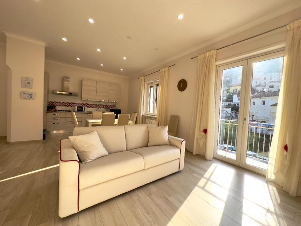 a living room with a white couch and a kitchen at Blu costiera Casa Vacanze in Maiori