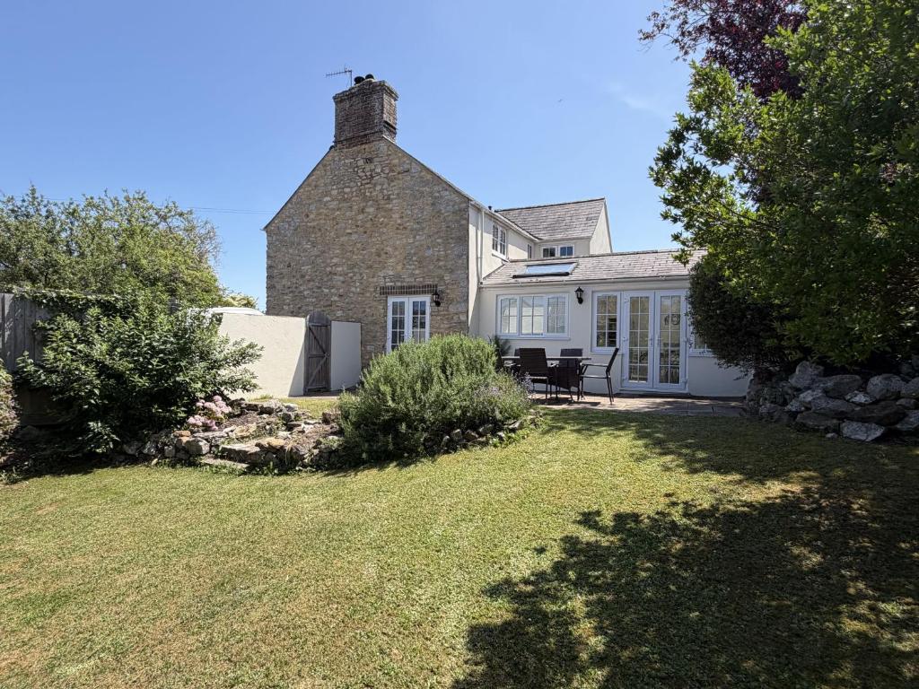 an old brick house with a grass yard at Fisherbridge Cottage in Weymouth