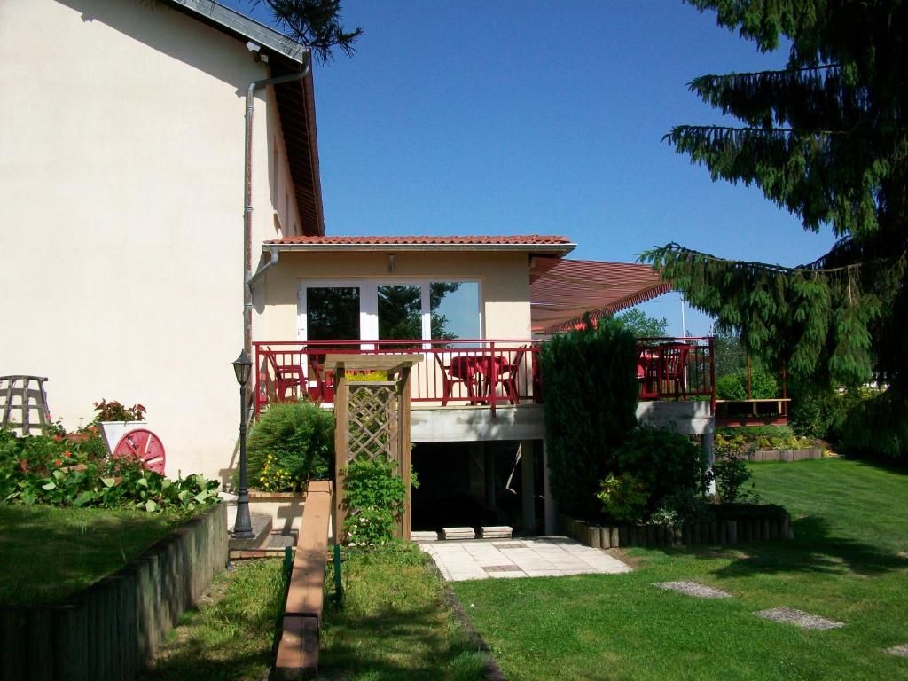 une maison dotée d'un balcon avec des chaises rouges. dans l'établissement Relais Vosgien - Hôtel Restaurant "la Table de Sophia", à Saint-Pierremont