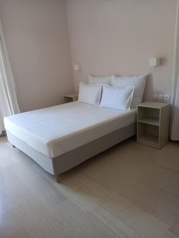 a white bed with white pillows and a night stand at Narika Aether in Kamena Vourla