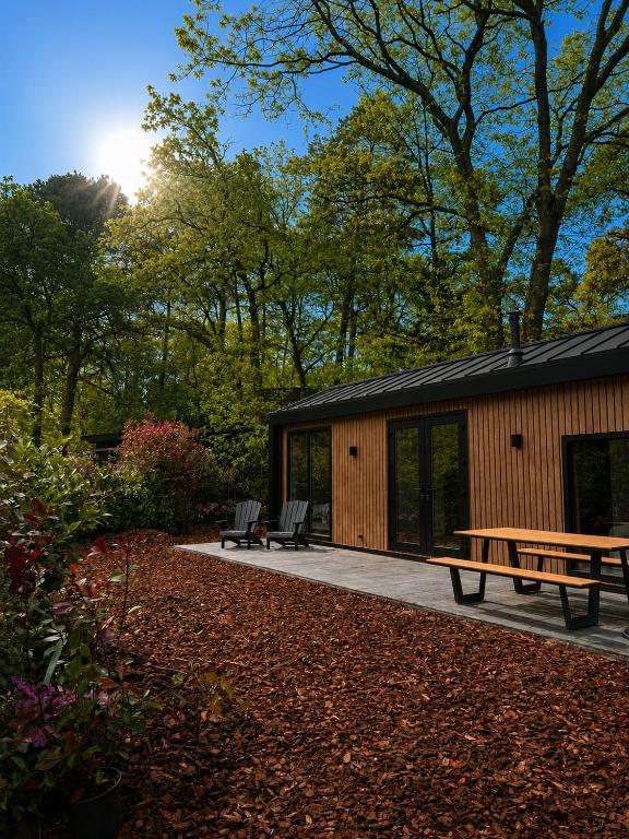 a cabin in the woods with a picnic table and benches at Huisje Mae in Nunspeet