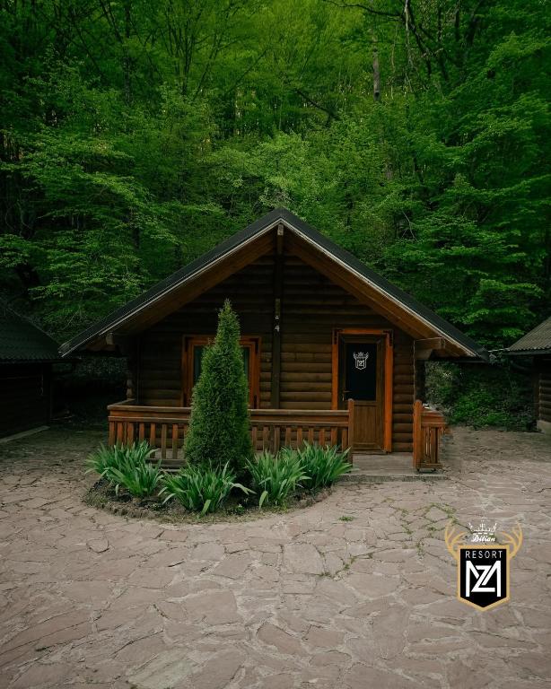 a log cabin with a tree in front of it at Resort Maja e Zezë in Gnjilane