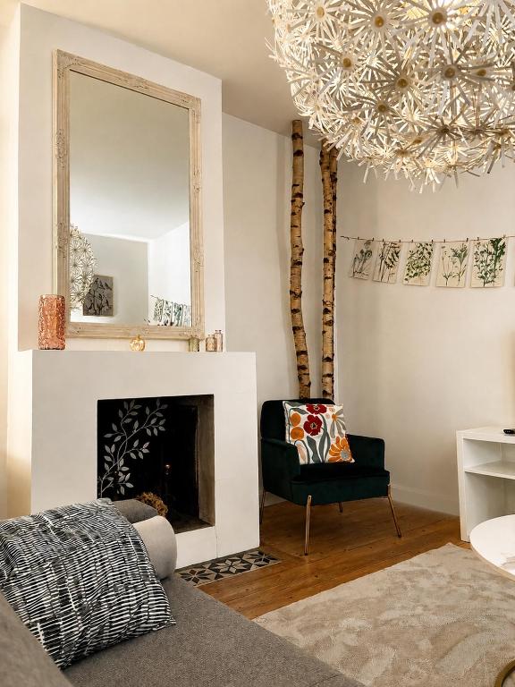 a living room with a mirror and a chair at Gîte La maison bleue proche Epernay in Chaltrait