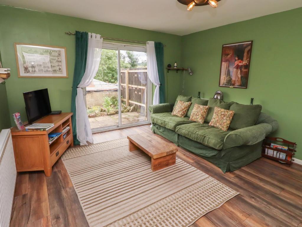 a living room with a green couch and a window at Flodden Apartment in Wooler