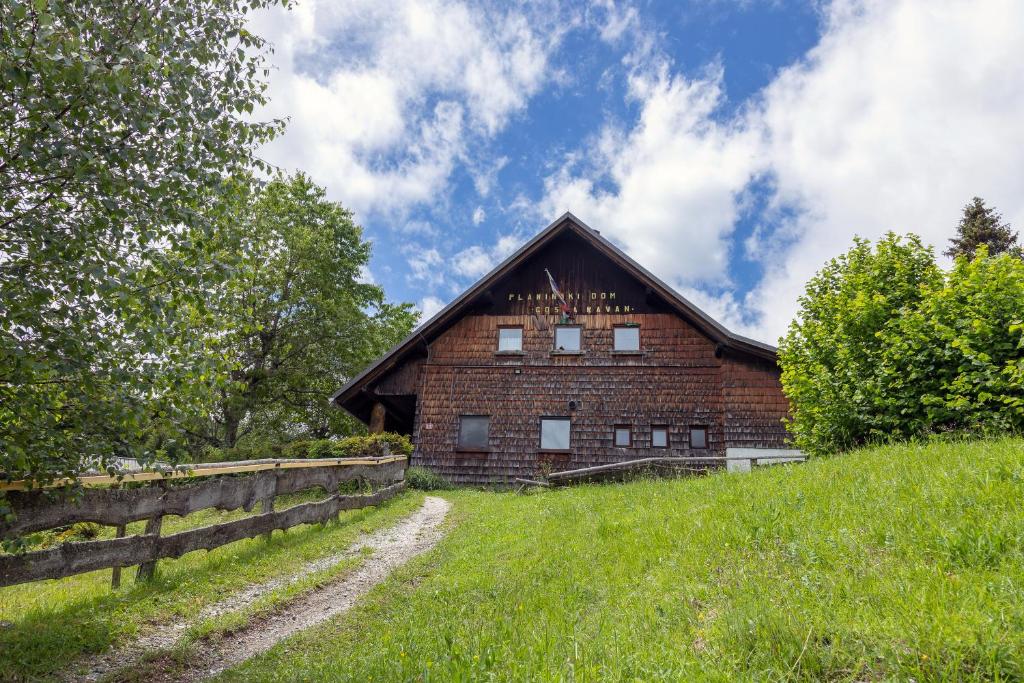 a brick barn on a hill with a fence at Alpine Lodge Goška Ravan in Radovljica