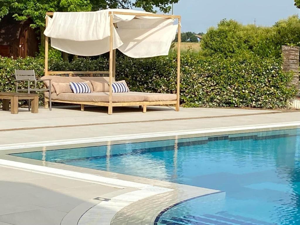 a couch and an umbrella next to a swimming pool at Villa Monet in Castiglione di Ravenna