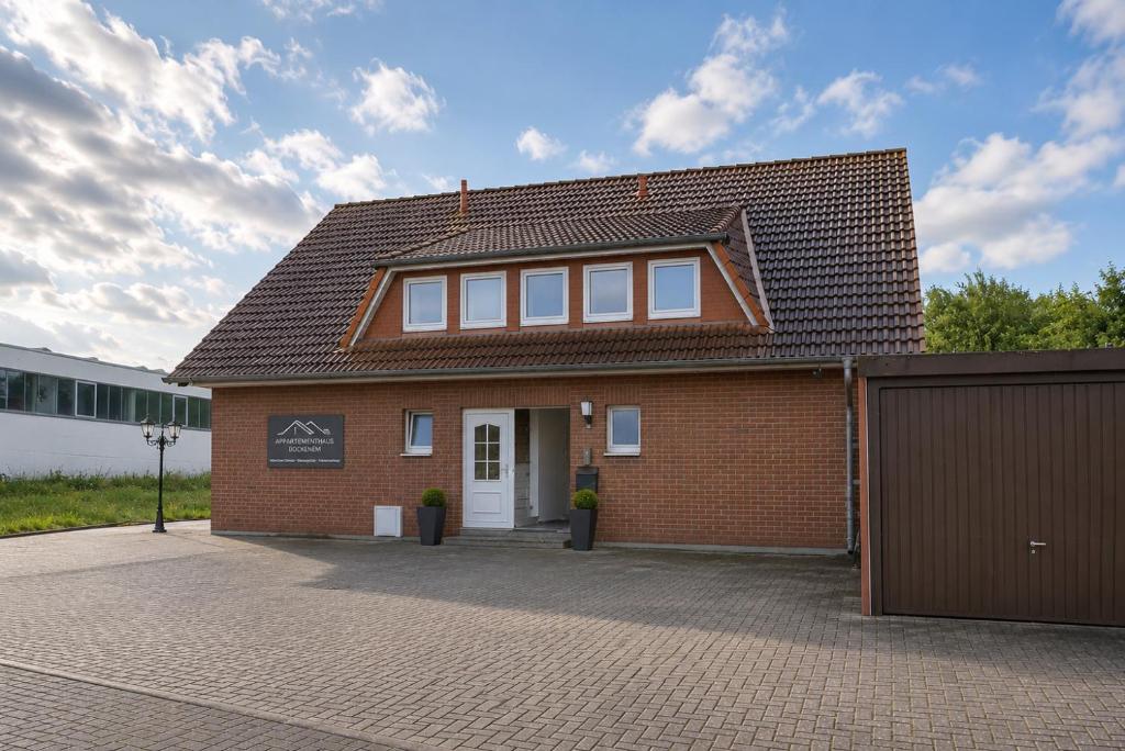 a red brick building with a brown roof at Messeappartementhaus Bockenem direkt an der A7 in Bockenem