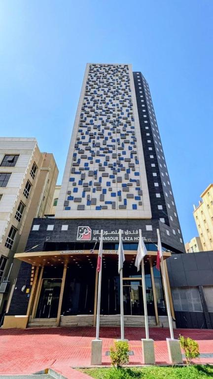 a tall building with flags in front of it at Al Mansour Plaza Hotel in Doha