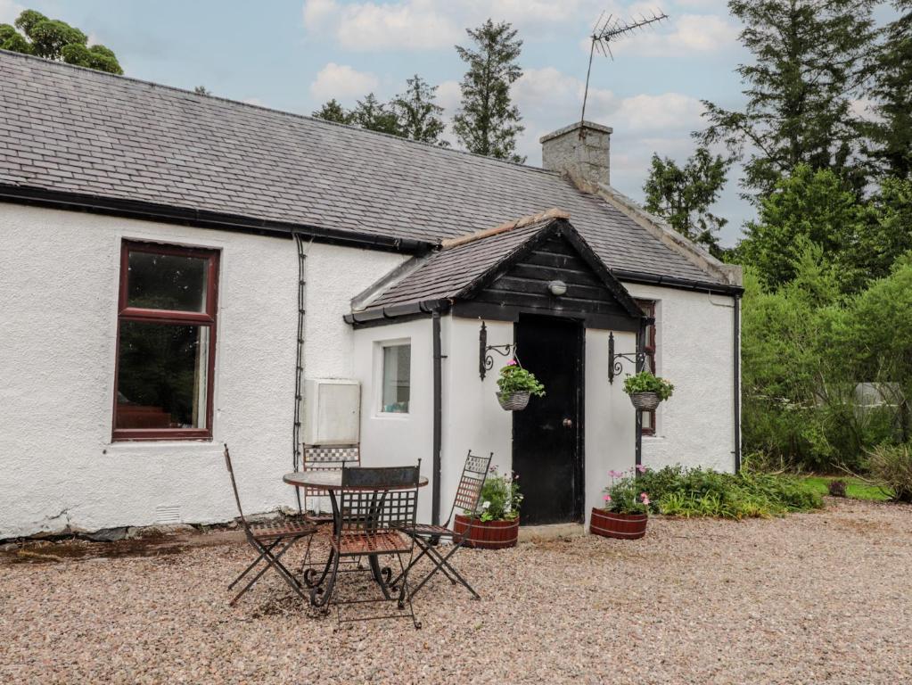 a white cottage with a table and chairs in front of it at Keepers Cottage in Peterhead