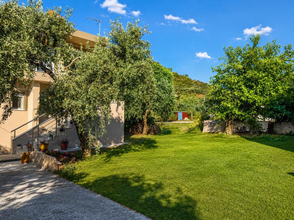a green yard with trees and a building at Katsanikos Apartments in Prinos