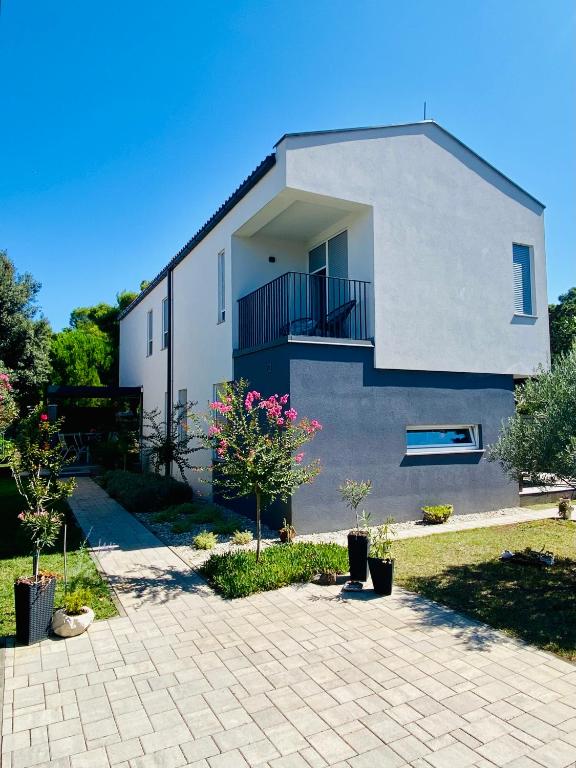 a white house with a balcony and some trees at Villa Ida in Punat
