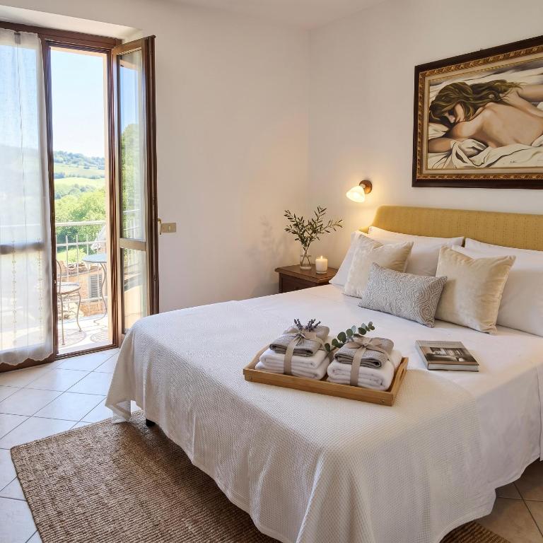 a bedroom with a large white bed with a balcony at Casa Stella in Sarnano