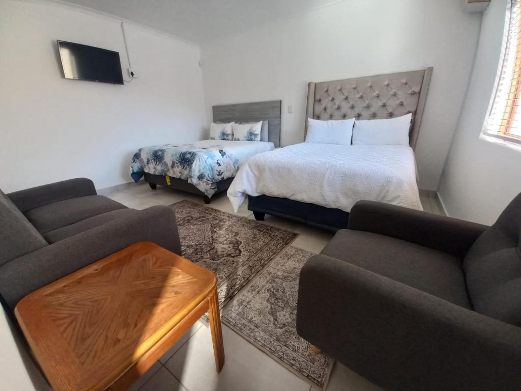 a living room with a bed and a couch at Sintha guest house in Kraaifontein