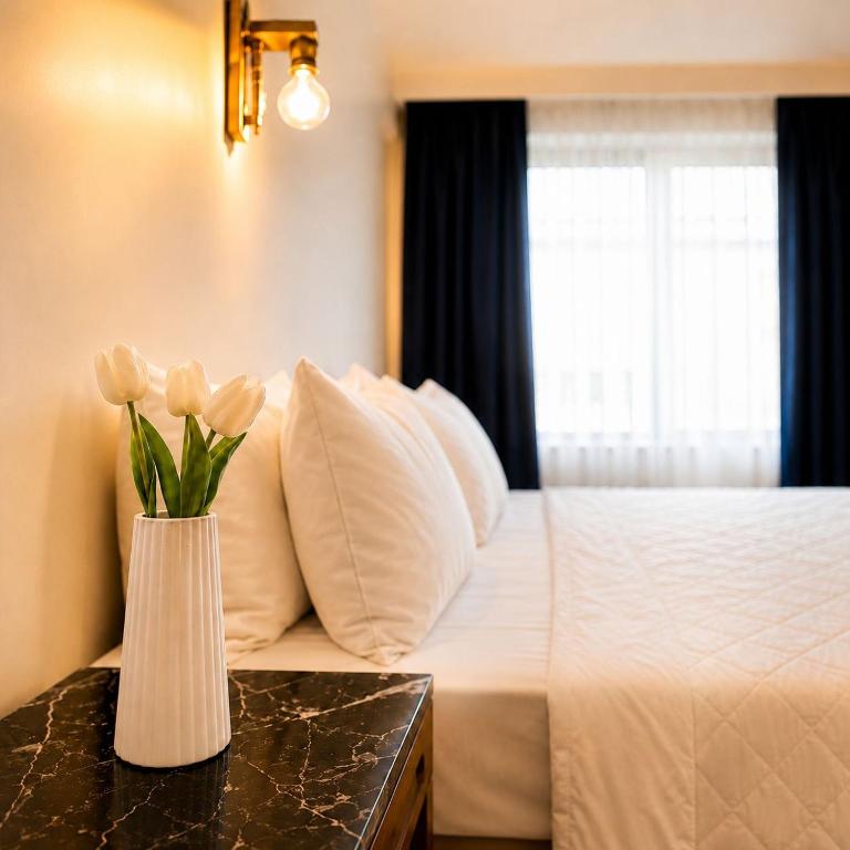 a bedroom with a bed with a vase of flowers on a table at Blue Sea Hotel in Tuzla