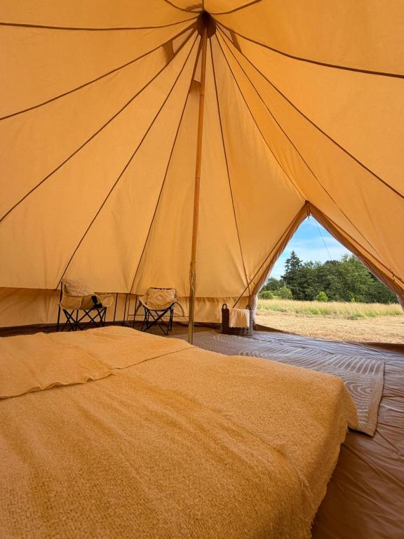 a large tent with two chairs in front of a bed at Glamping Fit in the wild in Forest Row