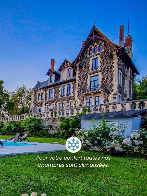 a large brick building with a sign in front of it at Manoir des Rêves Sauvages in Parentignat