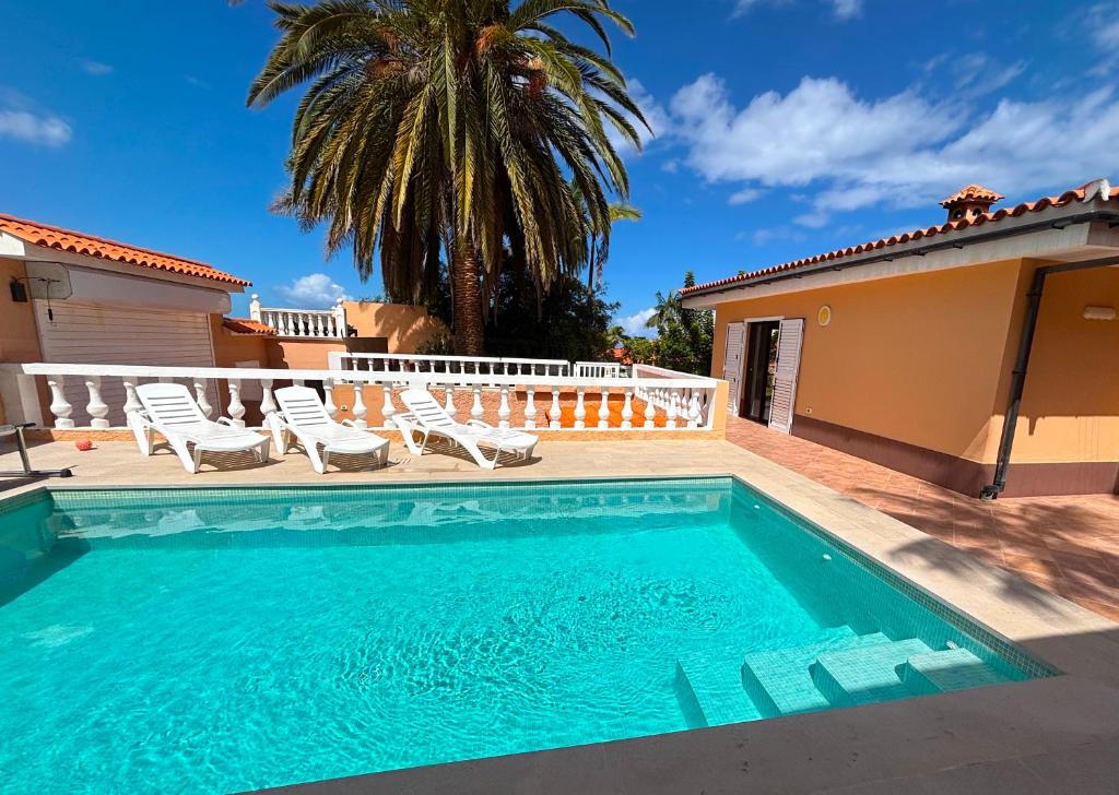 a swimming pool with chairs and a house at Villa Casa Papaya - All Year Heated Pool in La Orotava