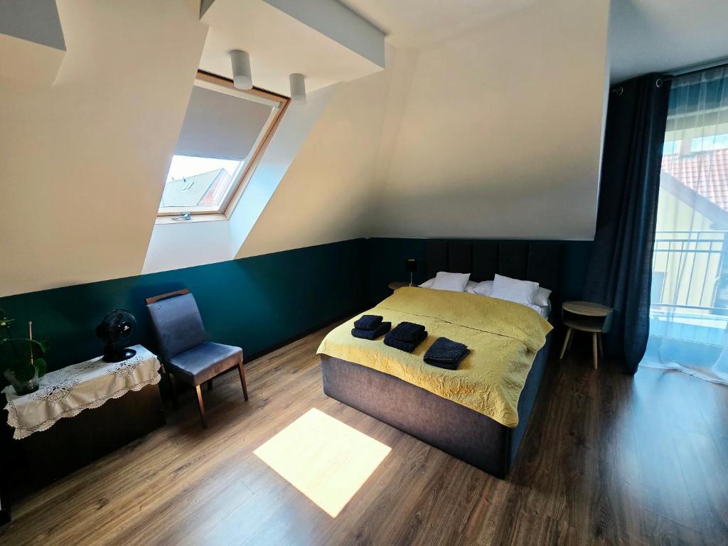 a bedroom with a bed and a chair and a window at Szary odpoczynek na piętrze - wieś Pogórze, dla zmotoryzowanych in Pogórze