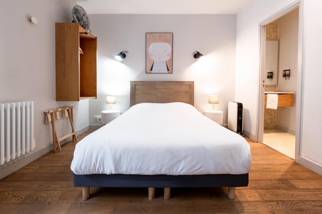 a bedroom with a large white bed and two lights at Apparts de l'Oncle Louis in Versailles