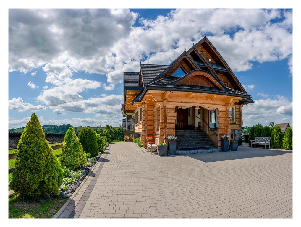 a wooden house with a roof on a brick driveway at Willa na Borku in Ciche