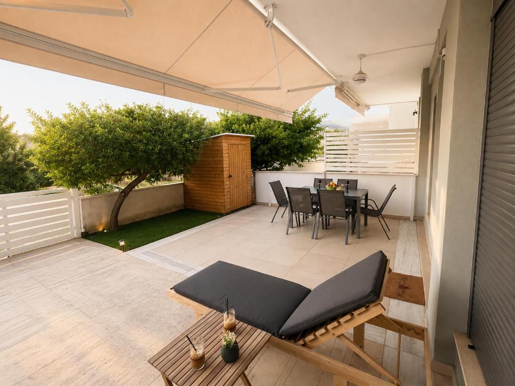 a patio with a table and chairs and an umbrella at Summer Dream Escape Apartment in Gerakini