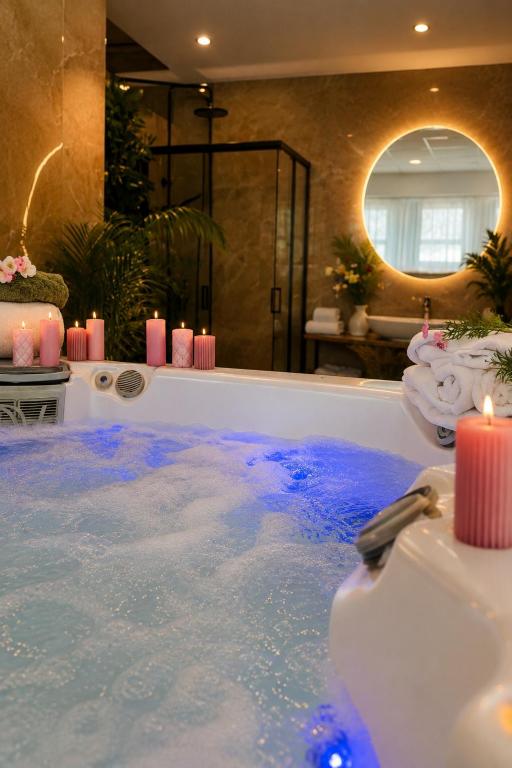 a bathroom with a tub filled with blue water at Plaza Hotel Gyula in Gyula