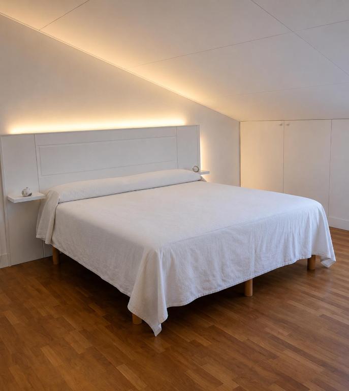 a large white bed in a room with wooden floors at Casa Olgaluna - Art Home in La Spezia