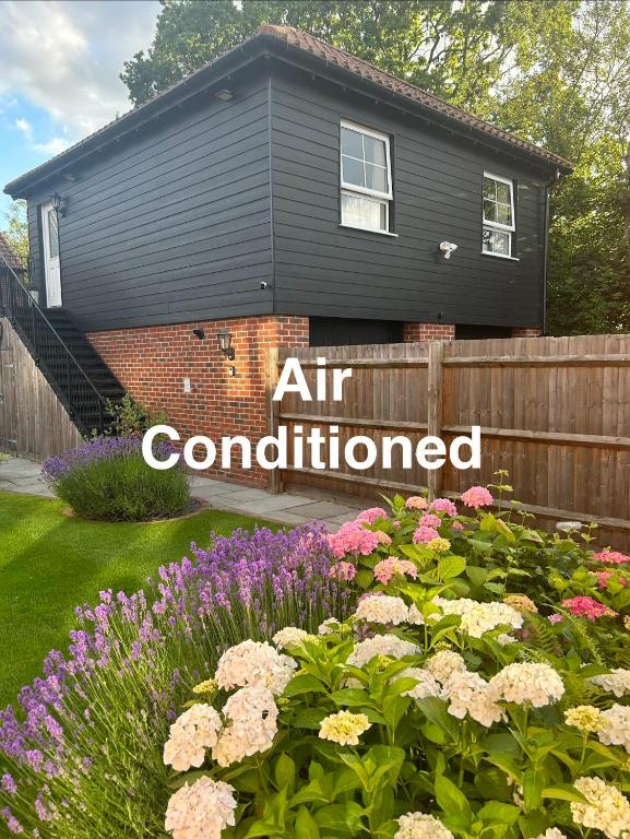 a house with an air conditioned sign in a garden at Stansted Coach House - Apartment Hotel in Elsenham