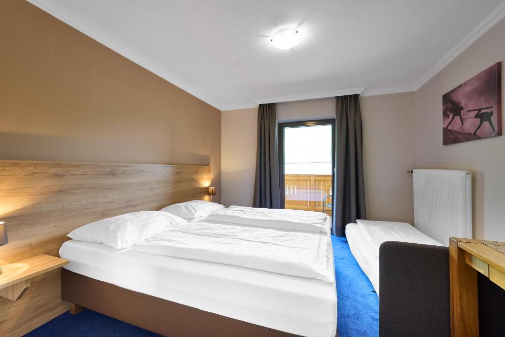 a hotel room with two beds and a window at Alpina`s Beds & Boots in Obertauern