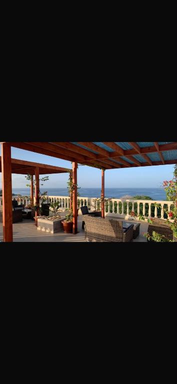 a porch with chairs and a pergola with the ocean in the background at Casa de los Encantos in Vila do Porto