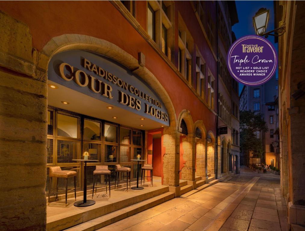 ein Gebäude mit einem Restaurant an einer Straße bei Nacht in der Unterkunft Cour des Loges Lyon, A Radisson Collection Hotel in Lyon