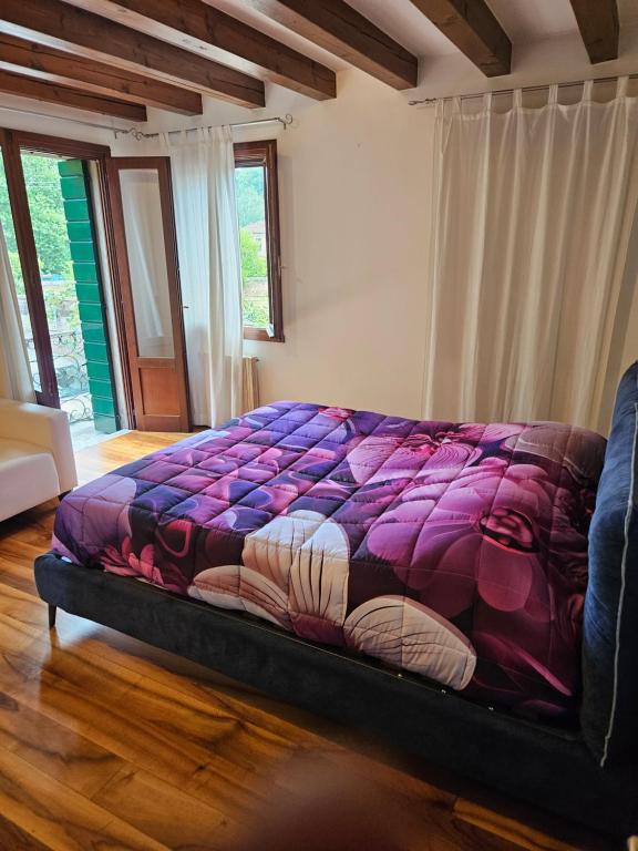 a bed in a bedroom with a purple comforter at Antica Dimora Confine in Mira