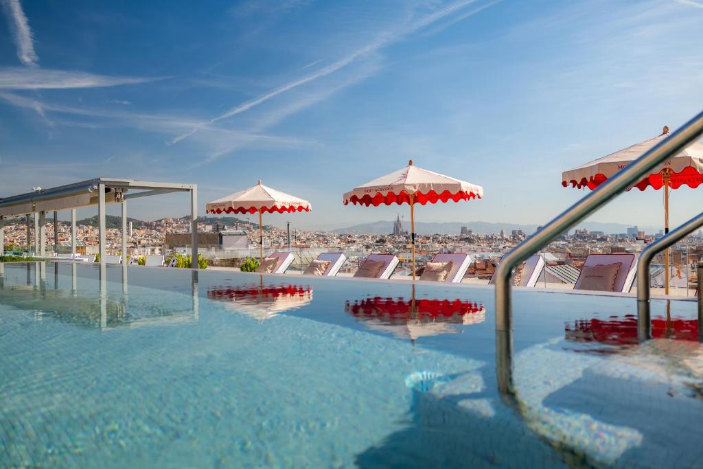a swimming pool with umbrellas and a view of a city at InterContinental Barcelona by IHG in Barcelona