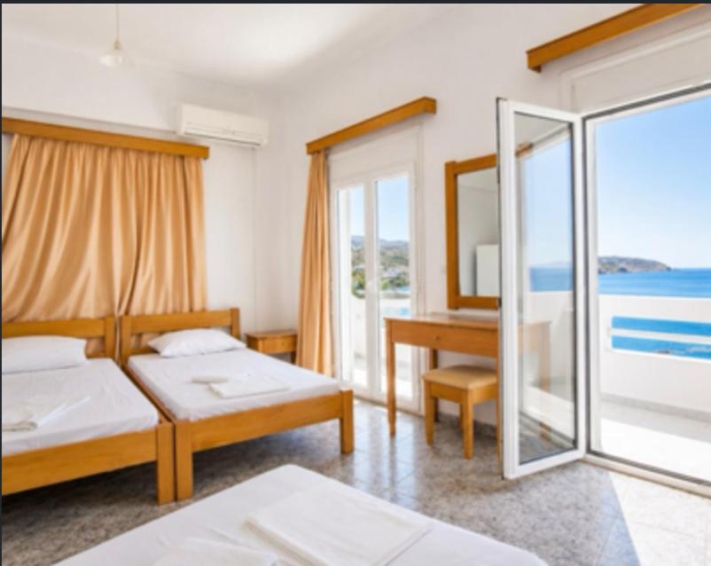 a bedroom with two beds and a desk and a window at Triton Sea View Studios in Tsoutsouros