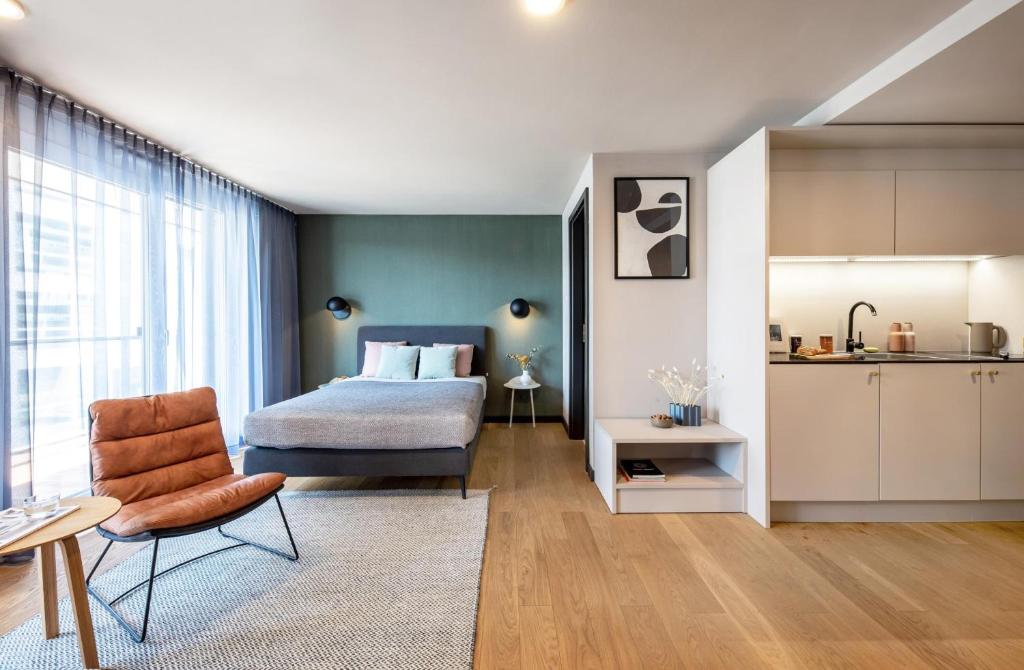 a bedroom with a bed and a chair and a kitchen at ipartment Boeblingen @HOME by Best Western in Böblingen