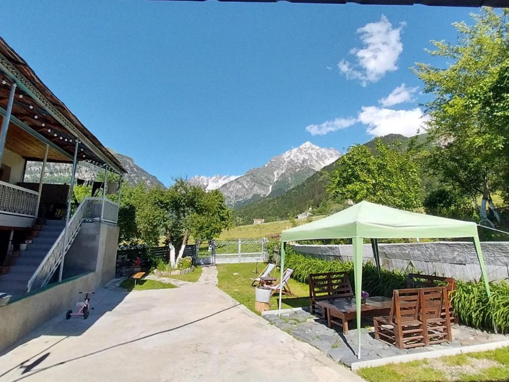 a green umbrella in a yard with a mountain at Guesthouse Leno in Tsaldashi