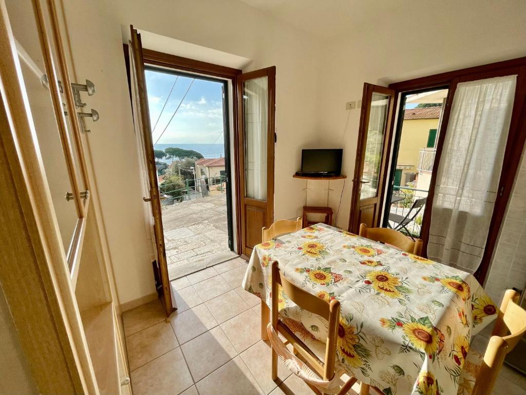 a dining room with a table and a door to a balcony at Rosmarino Apartment in Seccheto