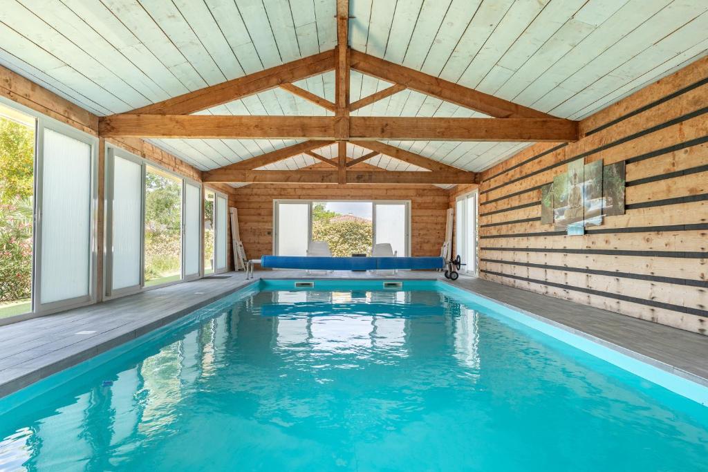 a swimming pool in a house with a wooden ceiling at Chambres D'hotes Le Cocon De Lily in Saint-Avit