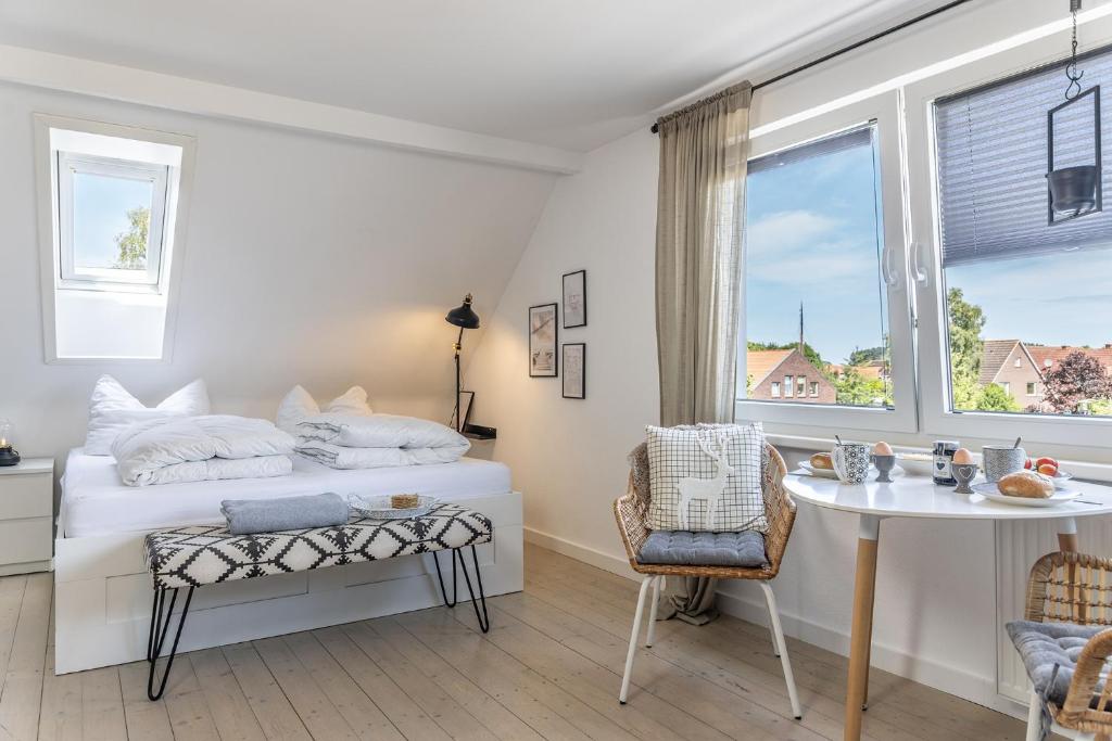 a bedroom with a bed and a table and a window at 50112 Ferienwohnung "Coco" in Carolinensiel