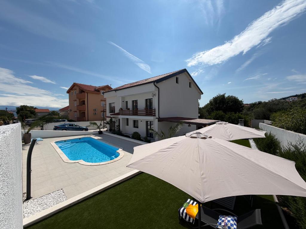 a house with an umbrella and a swimming pool at Apartment Ana Pool Residence in Preko