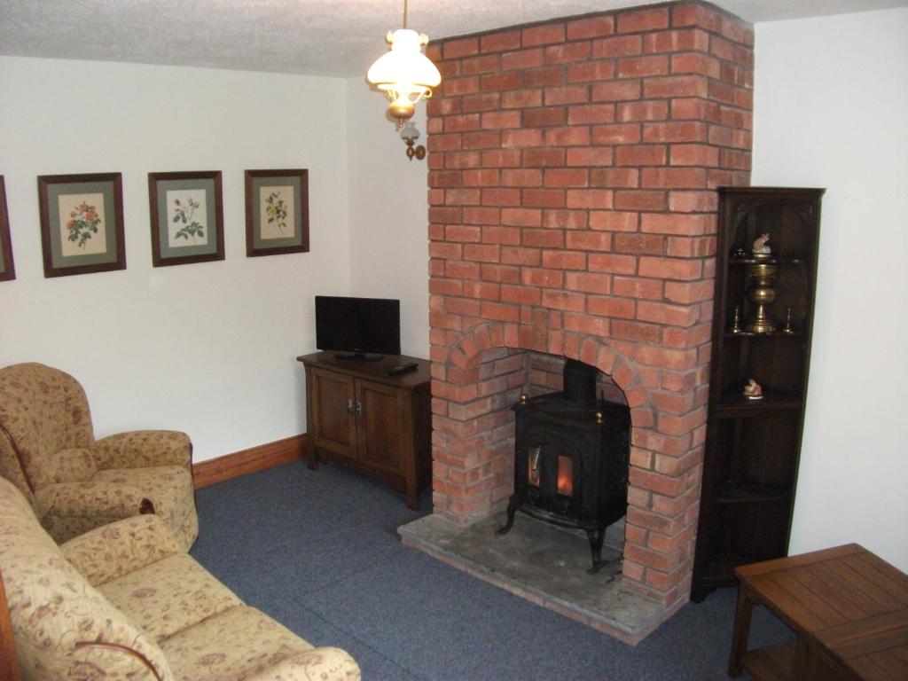 a living room with a red brick fireplace at Bryn Cottage in Llandderfel