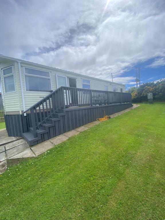 a mobile home with a porch and a fence at Angie Bs Beach Haven in Groomsport