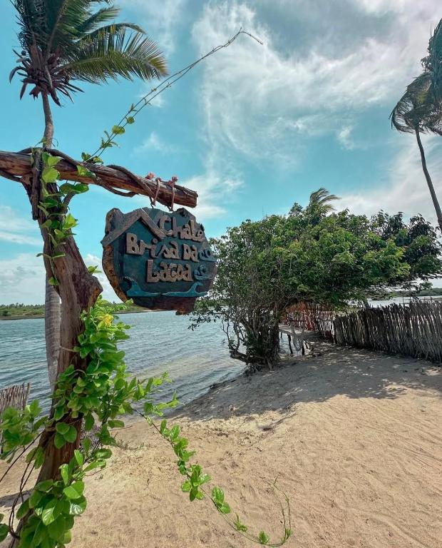 a sign on a beach next to the water at Chalé Brisa da Lagoa in Icaraí